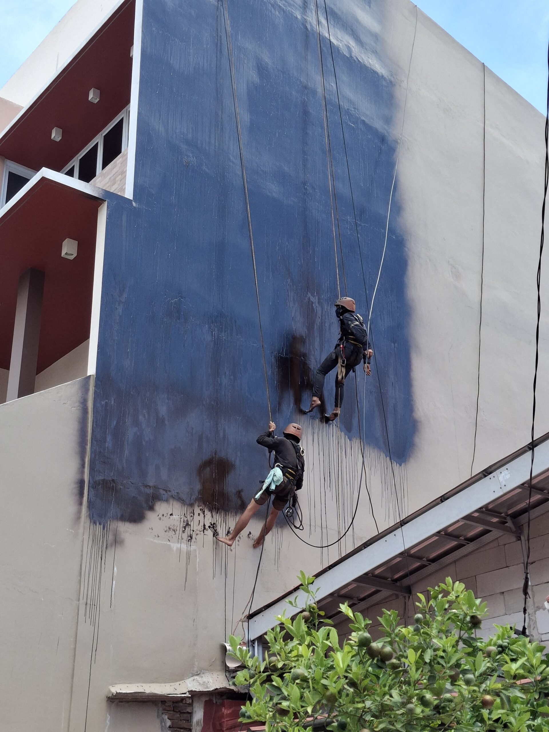 Tim Subur Jaya Aspal mengaplikasikan waterproofing aspal cair pada dinding dengan akses tali