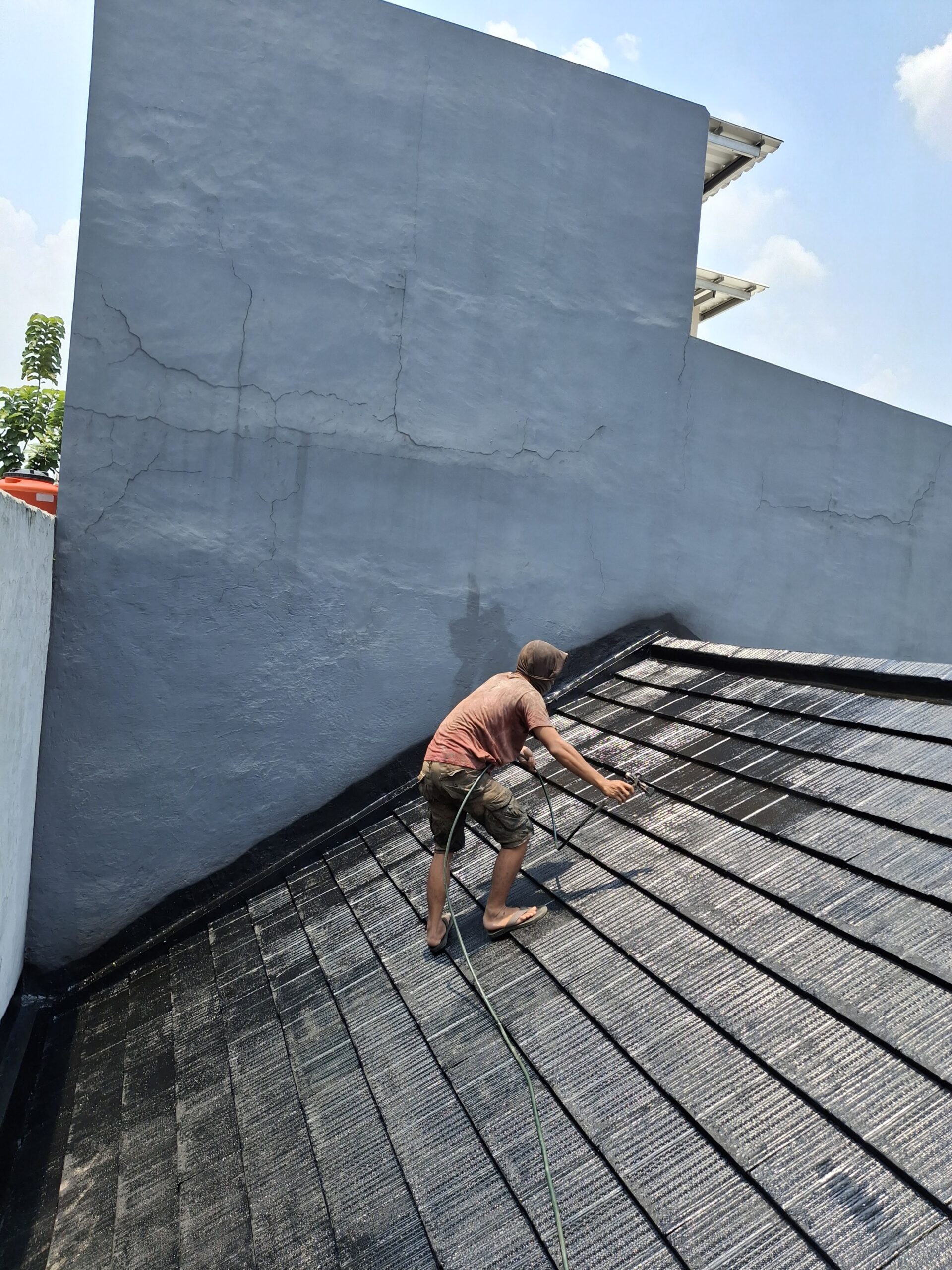 Pekerja mengaplikasikan waterproofing pada bidang genteng beton milik proyek Subur Jaya Aspal