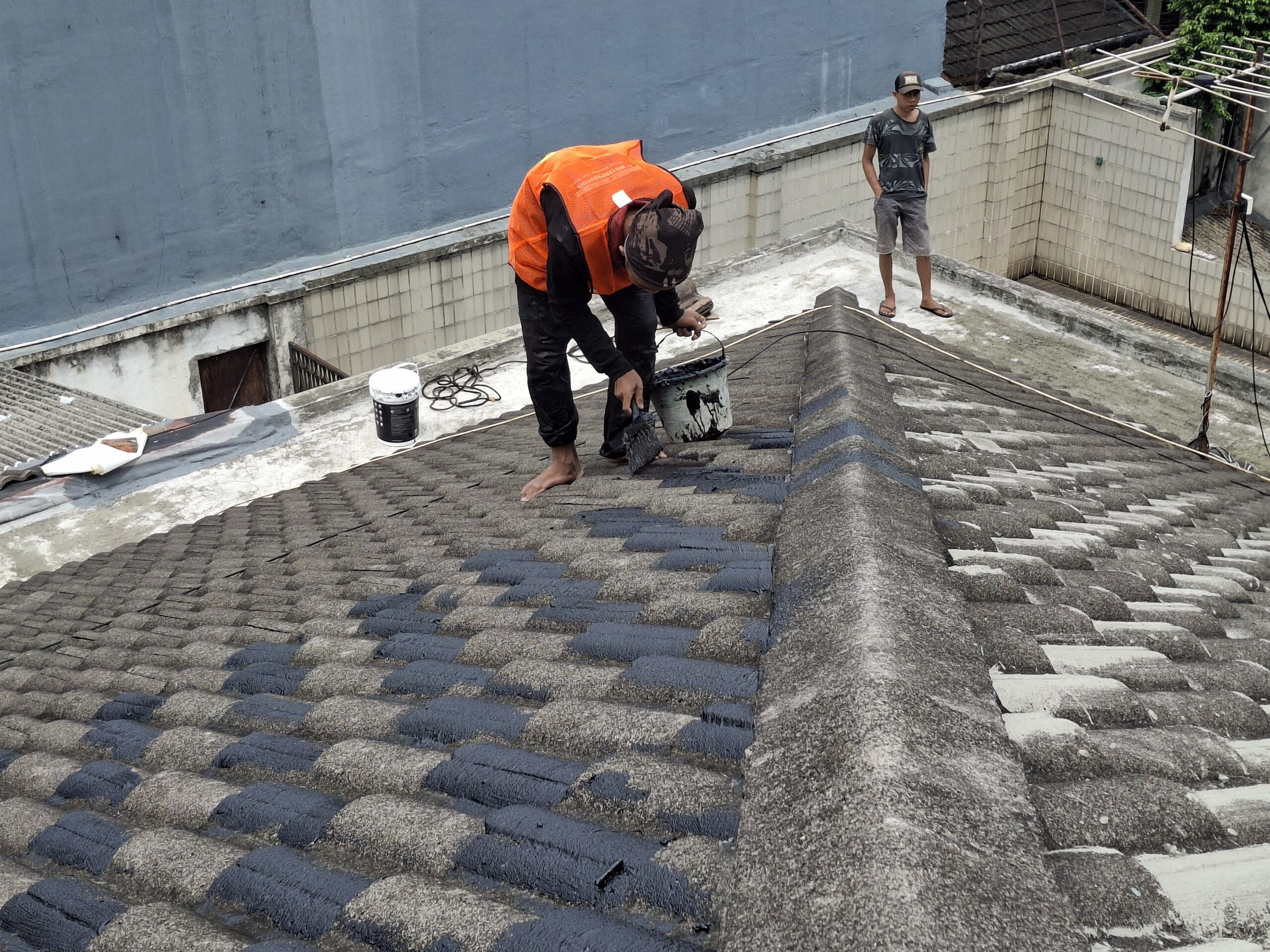 Pekerja Subur Jaya Aspal mengaplikasikan lapisan waterproofing pada genteng beton