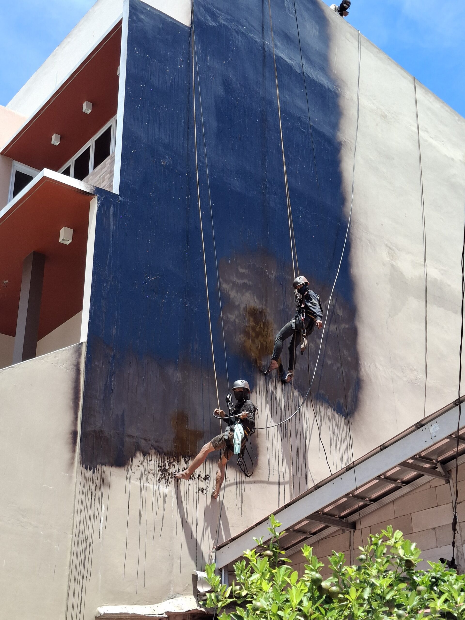 Tim Subur Jaya Aspal mengaplikasikan waterproofing dinding dengan rope-access di Kelapa Gading Jakarta Utara
